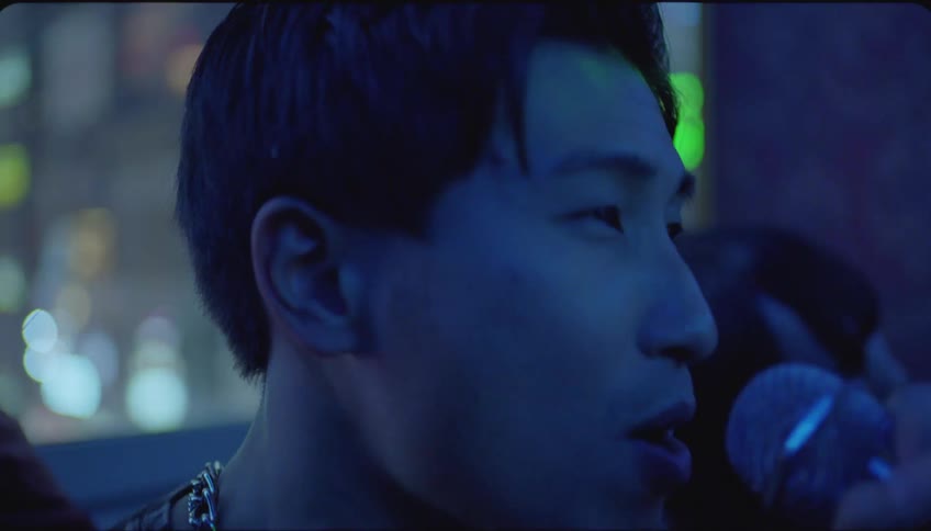 Man sings karaoke into a microphone at a club with friends looking on