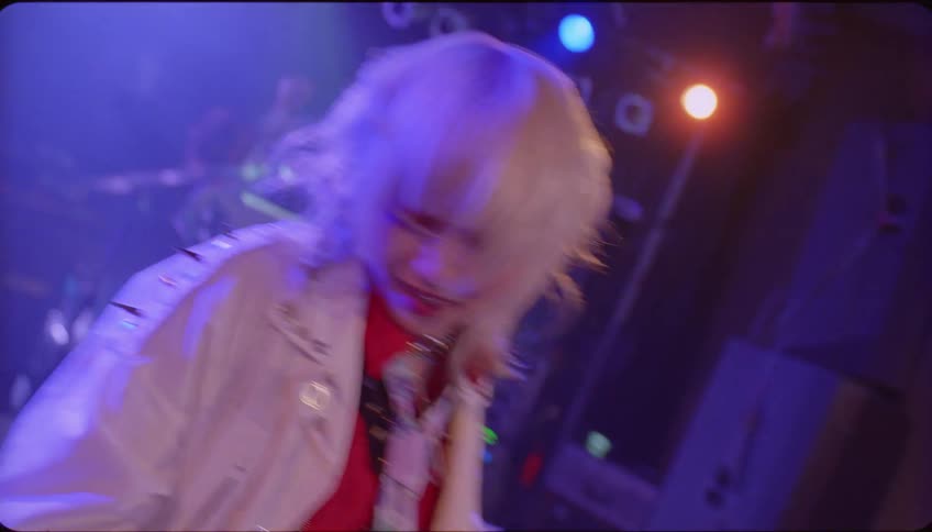 A female performer sings and dances on stage to an exuberant crowd