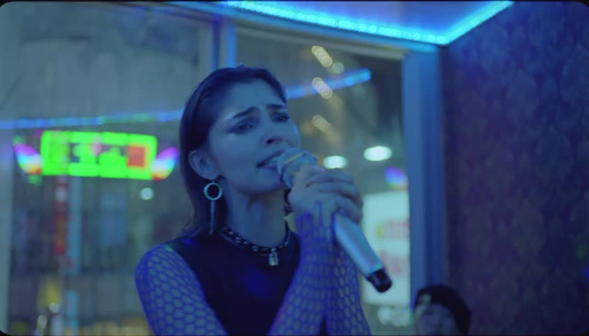 Portrait of a woman singing at a karaoke in a pub with her friends sitting and watching