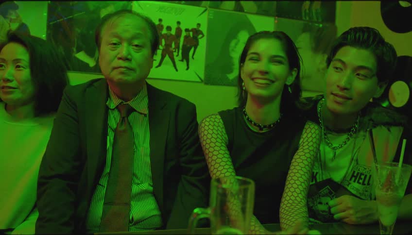 Friends and family sitting in club against walls decorated by albums and recordspose for a picture