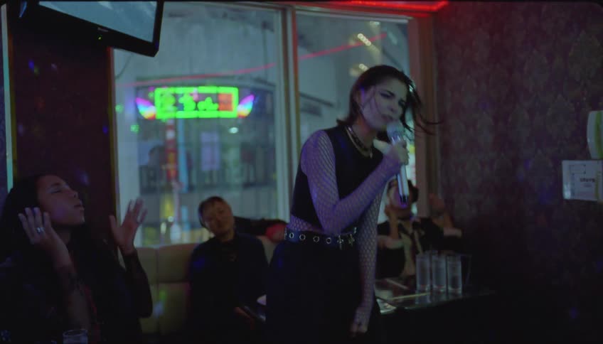 Woman singing into a microphone next to her friends cheering