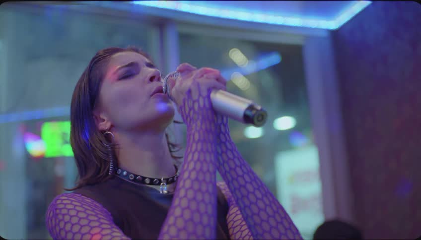 A woman is singing in a night club to some people sitting