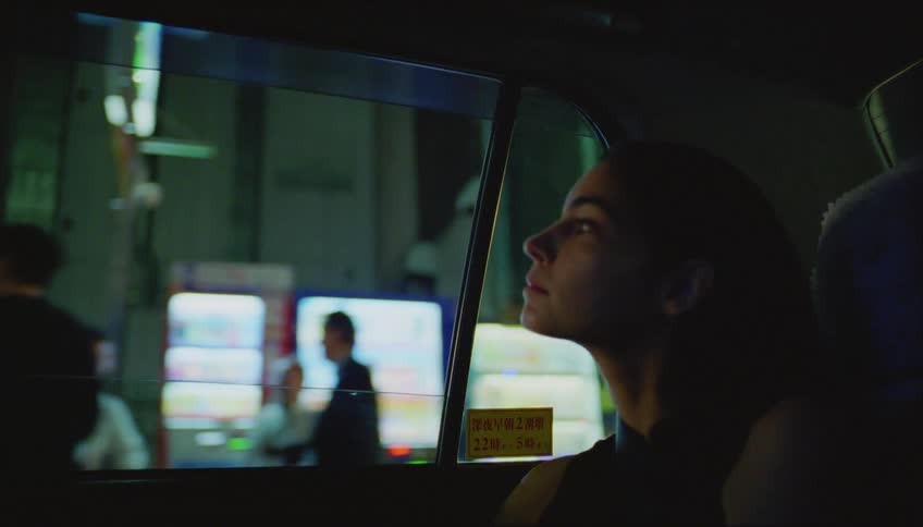 Portrait of a young woman in a taxi enjoying the view of the nighttime city