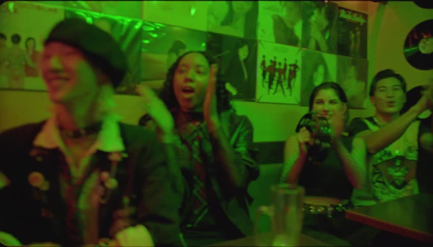 People clapping for a man holding a microphone in a pub at night