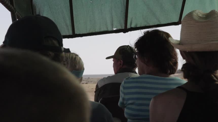 People are sitting in a vehicle looking over a desert