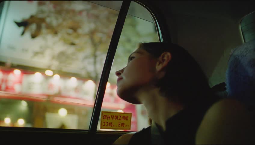 Passenger in cab looks out window while passing through downtown at night