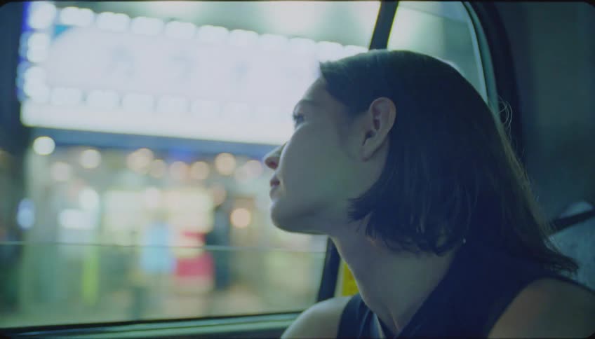 Portrait of a young woman observing the night city view from inside a taxi