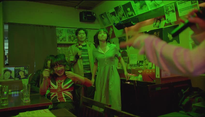 Friends in a pub with one of them singing karaoke and everyone in the same happy vibe