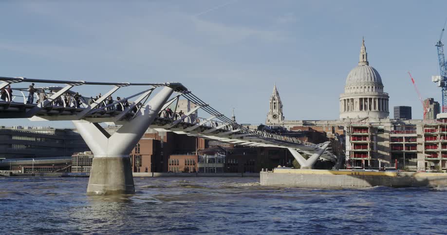 A ferry passing under a bridge full of people