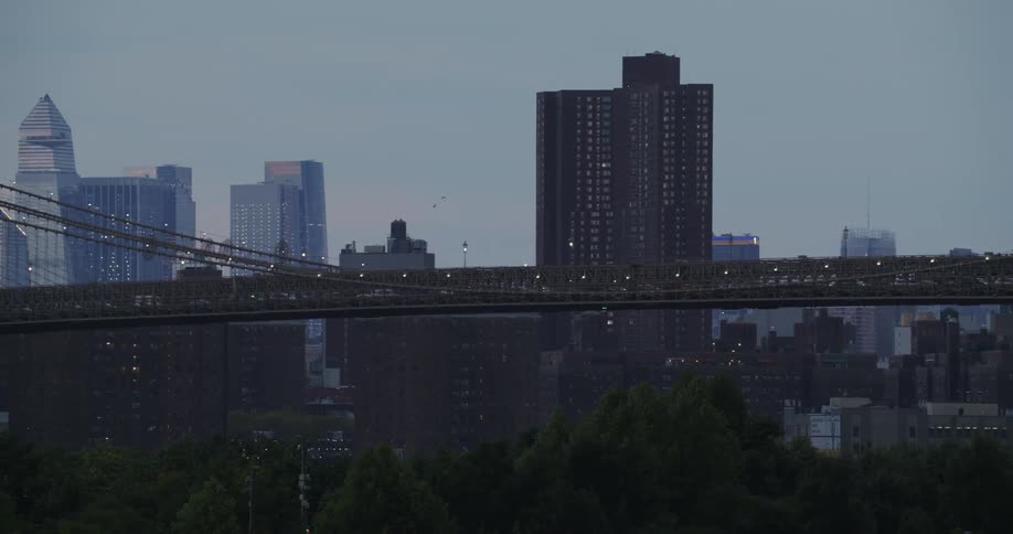 A suspension bridge spans a river as cars traverse it