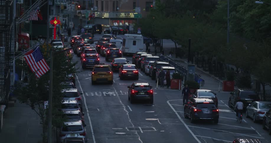 View of a busy street with cars stopping at a red traffic light in a metropolis