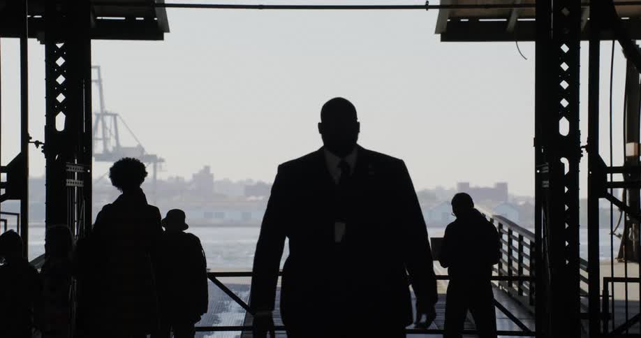 Silhouette of a man in a suit walking forward on a platform under the sea