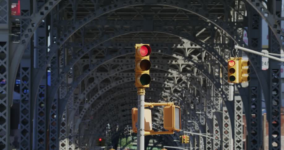 A traffic light changing from red to green on a clear day near a bridge