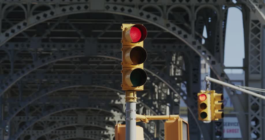 Traffic signals near a bridge changing colors at midday