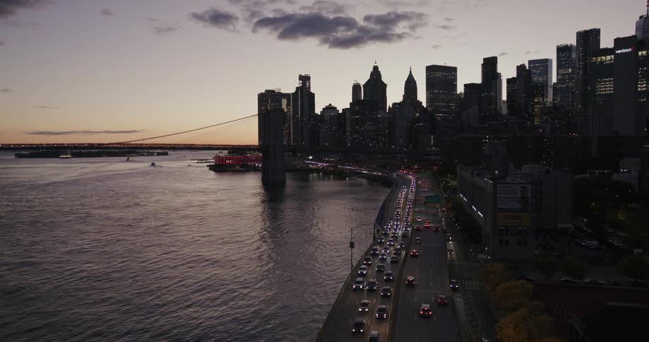 View of a metropolis by the sea under a purple evening sky with vehicles passing through intersections