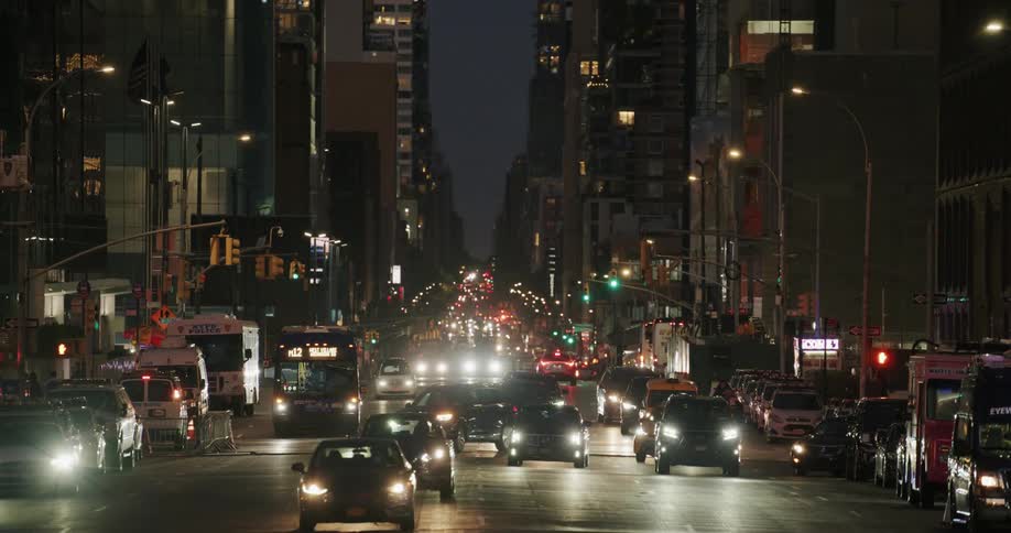 Pedestrians and vehicles move along busy city streets at night