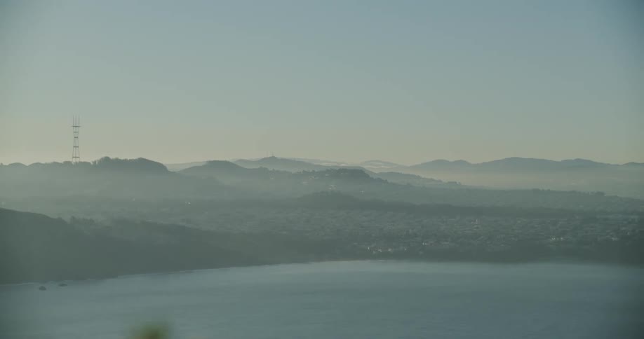 Aerial panorama of the sea and a mountain range with a city on the horizon in the morning