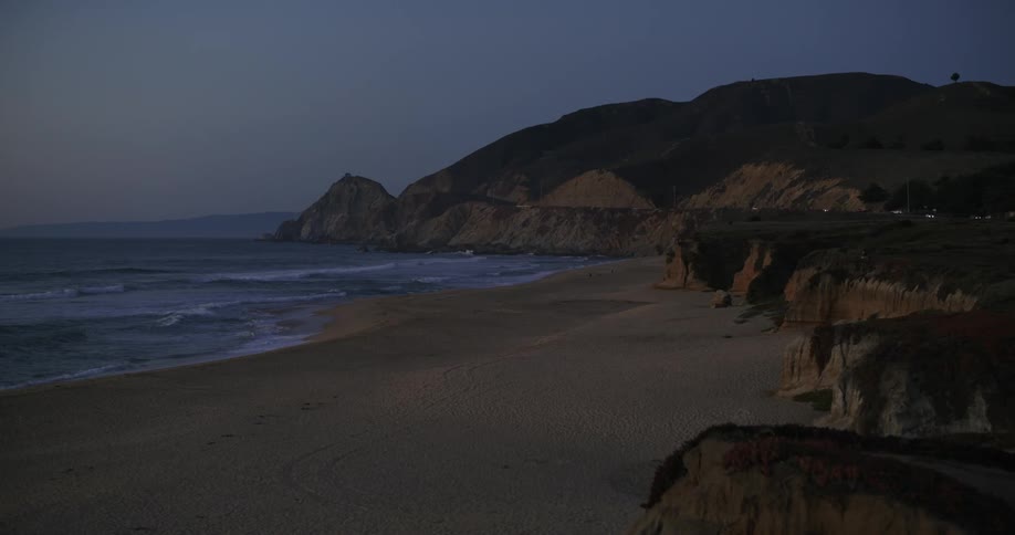 Landscape of a beach at the beginning of dusk with calm waves and the coastline