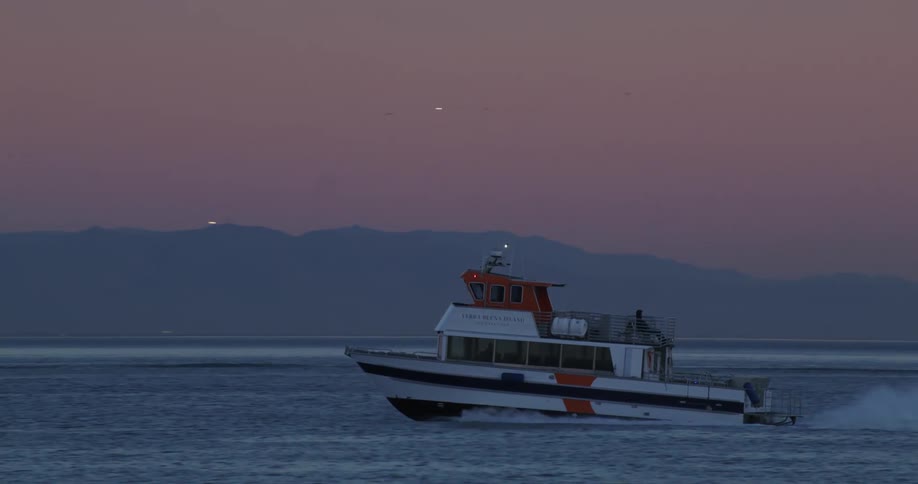 Boat moving through the sea on a morning with a pink sky