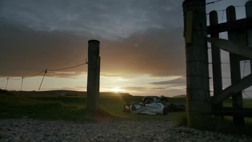 Several wooden fences stuck in the ground and the sun setting in the sky