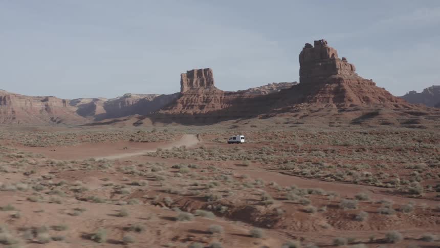 A van is parked off the road among buttes and mesa in the desert