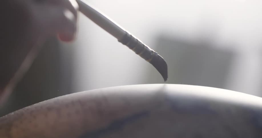 A person is painting a round item