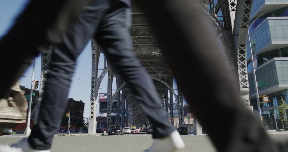 Vehicles drive through an intersection under an overpass in the daytime