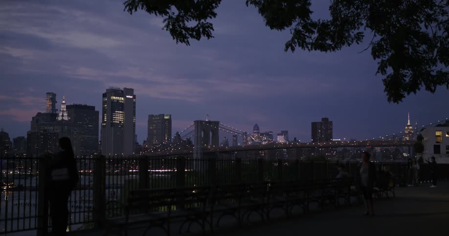 Cityscape and bridge seen from coastal promenade at dusk