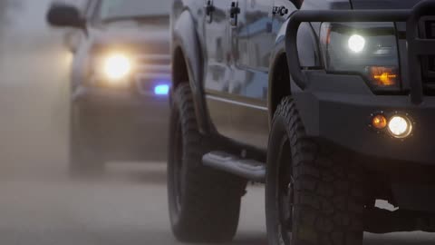 A large row of cars with police lights are traveling
