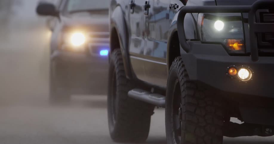 A large row of cars with police lights are traveling