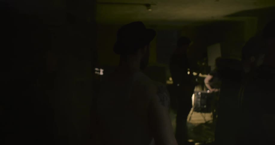 A man is walking down a dark hall towards a group of people