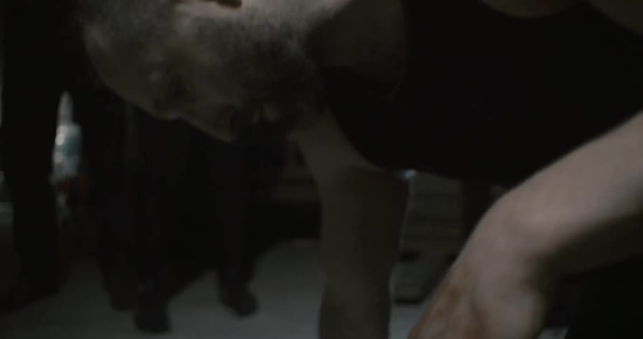 A man is bent over and spits blood onto the floor