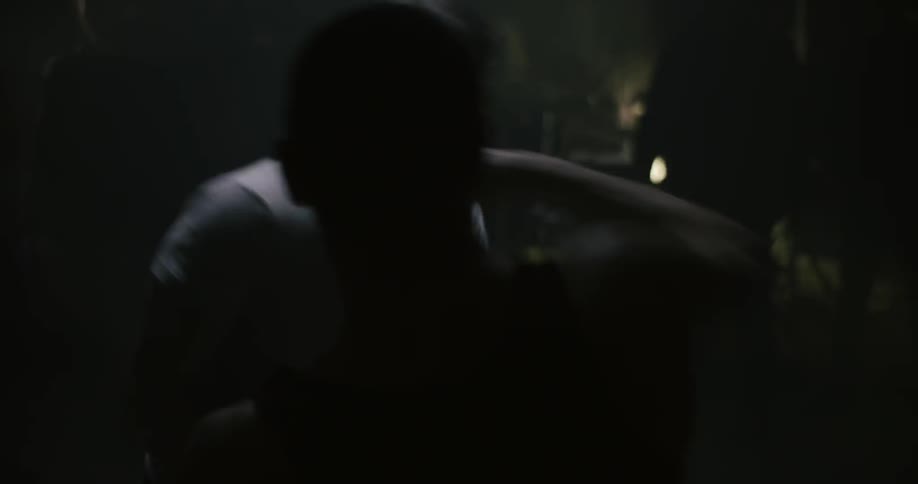 Two people are fighting in a dark room exchanging punches