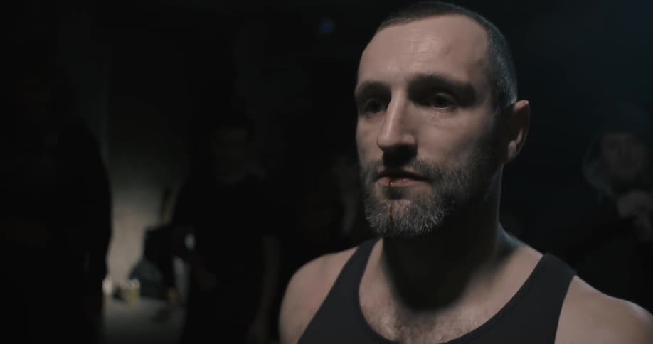 A man is bleeding and standing in a dark room