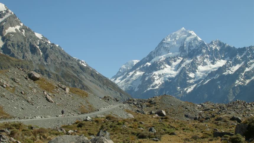 A person walks down a rocky path on a mountain