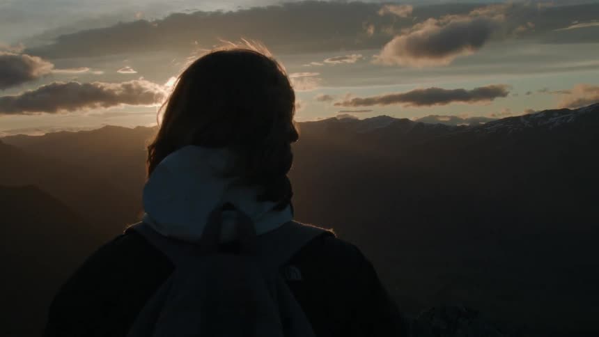 A woman watches the sunrise over a mountain