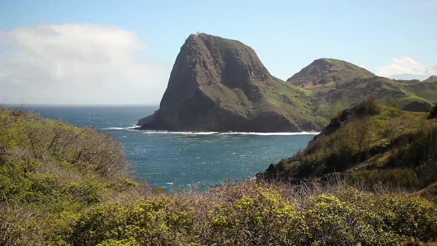 The wind is blowing the bushes on the mountains around the water