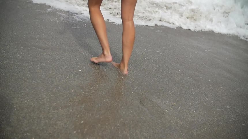A person walks barefoot on the beach