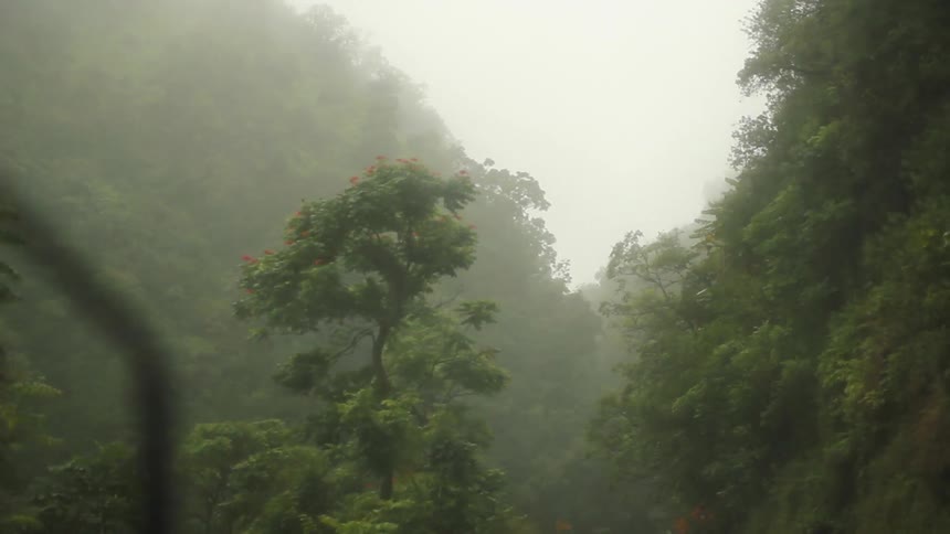 A vehicles passes on a winding road in the rain