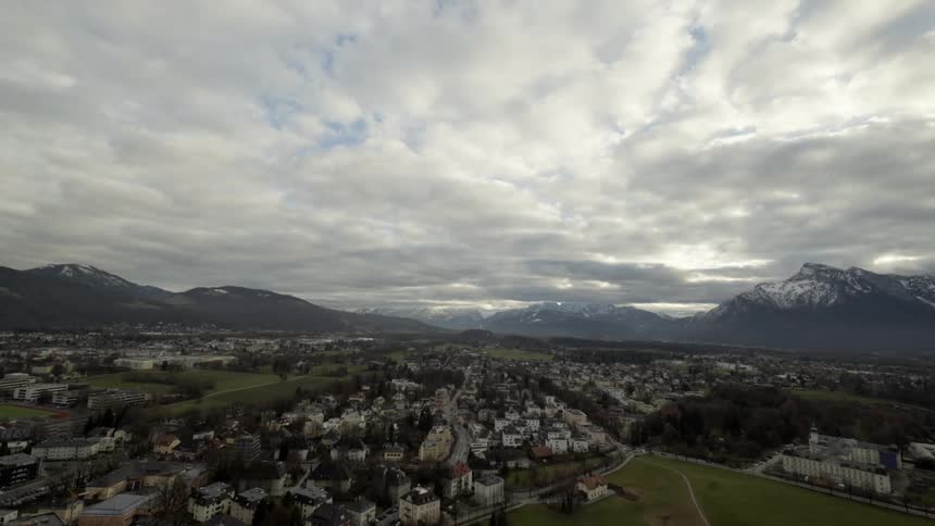 Clouds float over a city surrounded by mountains