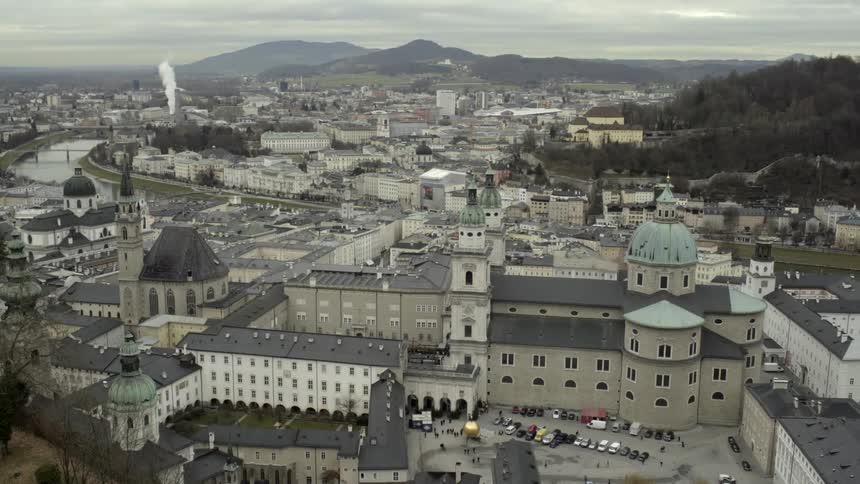 The city below has many long buildings and vehicles parked