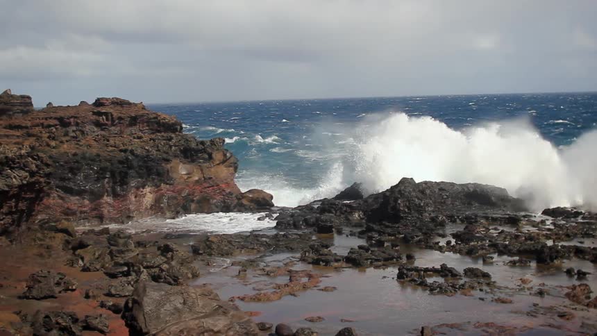 Waves crash spraying water everywhere on the coast line