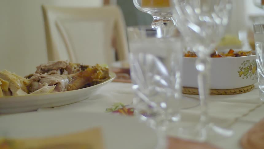 A person setting a platter of food on a table set for a meal