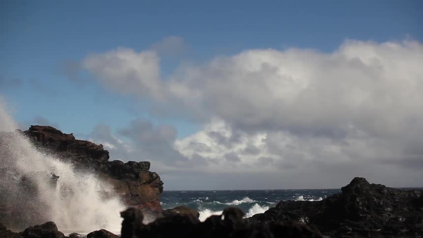 The waves hit the rocks hard spraying water high