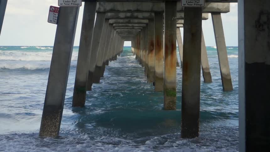 Waves crash against the boards propping up a pier