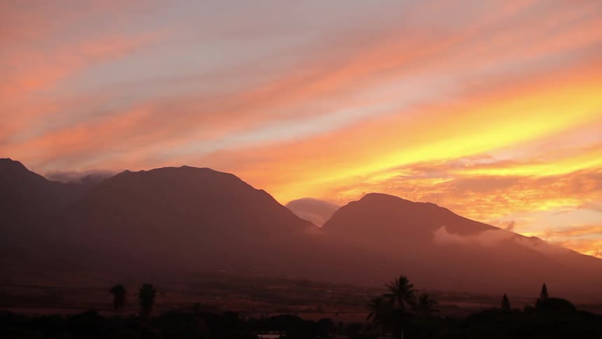 The sun is setting over the mountain range ahead