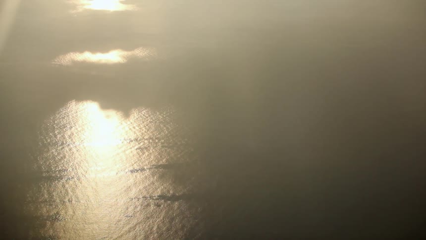 The skyline is full of clouds and the water is below is reflecting the sun