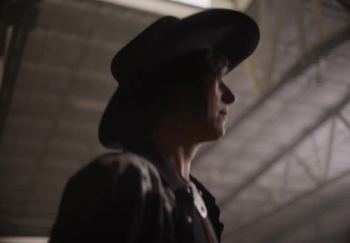 Woman dressed as a cowboy walking inside a warehouse