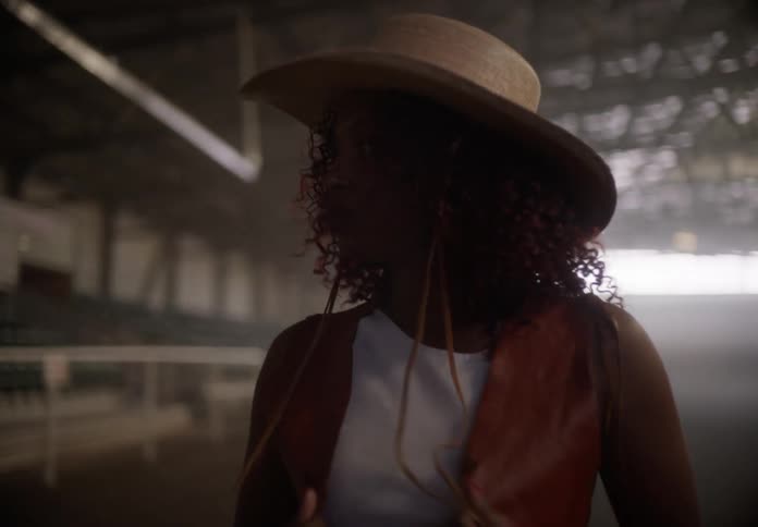 Female model stands in riding arena and models western style wear