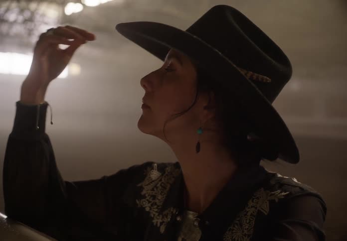 A woman puts on a cowboy hat and looks around